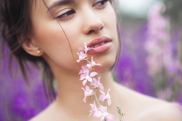 Sehr schöne junge Frau mit Blumen. Nahaufnahmeporträt der attraktiven Frau