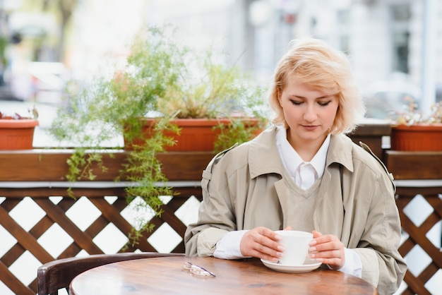 Sehr schöne junge Frau, sitzen im Cafe und trinken Kaffee oder Tee, Straßenansicht
