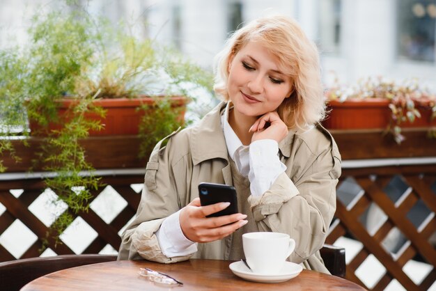 Sehr schöne junge Frau, sitzen im Cafe und trinken Kaffee oder Tee, Straßenansicht