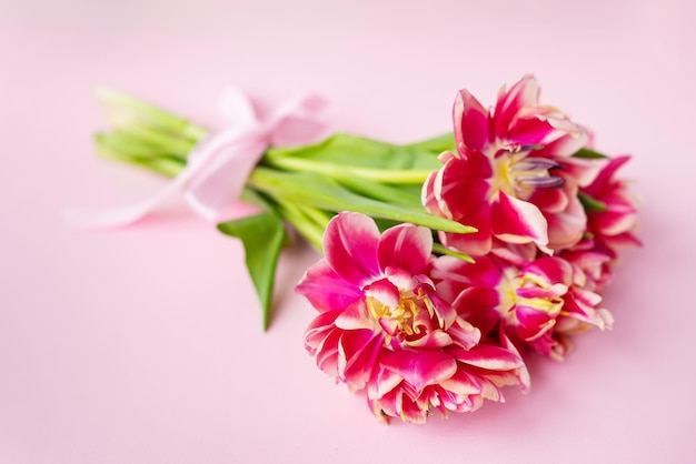 Sehr schöner Frühlingsstrauß aus Pfingstrose-Tulpen auf einem rosa Papierhintergrund in der Nähe Platz für eine Inschrift