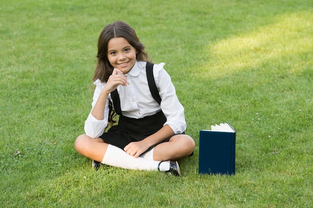 Seien Sie ein Leser hübsches Kind kleines Mädchen las Buchstudienliteratur für Kinder, die Spaß mit dem Buchwissenstag haben moderne Schulbildung glückliches Kindheitsjugendlichmädchen mit Buch auf grünem Gras