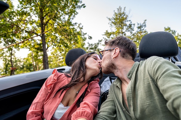 Seien Sie mein Valentinsgruß junges Paar Liebe Kuss Porträt Roadtrip für Flitterwochen, Freundinnen und Freunde, die sich in einem Cabrio küssen