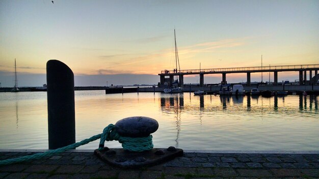 Foto seil, das bei sonnenuntergang an einem bollard gegen den fluss gebunden ist