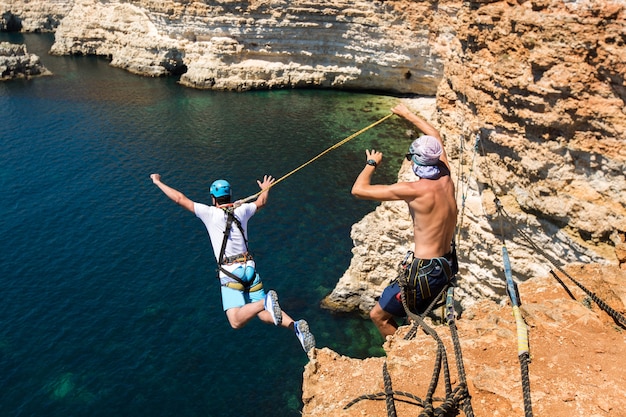 Seil springt von einer Klippe mit einem Seil im Wasser