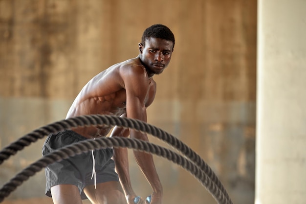 Seiltraining Sportler, der Kampfseile im Freien macht Schwarzer männlicher Athlet, der funktionelles Fitnesstraining mit schwerem Seil durchführt
