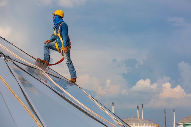 Seilzugangshöhensicherheit für männliche Arbeiter, die mit einem Knotensicherheitsgurt, Dachabsturzsicherung und Absturzsicherungs-Ankerpunktsystemen verbunden sind, die zum Aufsteigen bereit sind, Öltankkuppel auf der Baustelle