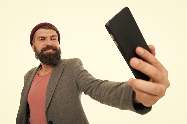 Sein bestes Selfie steht noch bevor Bärtiger Mann lächelt in die Selfie-Kamera Fröhlicher Hipster, der ein Selfie mit dem Smartphone in der Hand macht Perfektes Selfie aus jedem Winkel