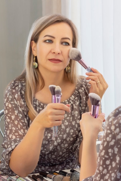 Sein eigener Maskenbildner. Frau macht Make-up vor einem Spiegel