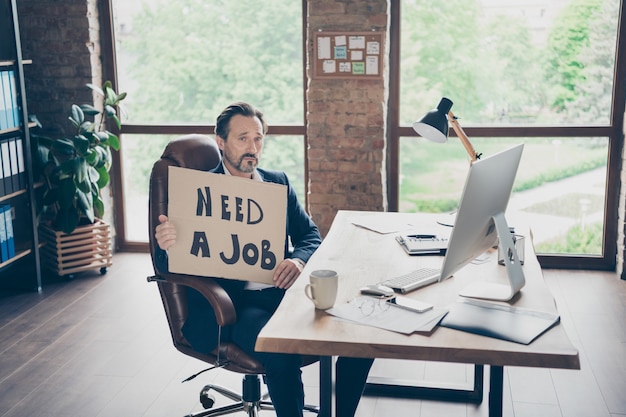 Sein er gefeuerter Agent Broker Finance Insurance Investor Ökonom Webspezialist Experte hält in Händen ein Plakat auf der Suche nach einem neuen Job an einem modernen Loft-Backstein-Industriearbeitsplatz