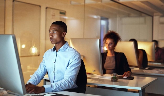 Sein Erfolg wächst von Minute zu Minute. Aufnahme eines jungen Geschäftsmannes, der bis spät in die Nacht am Computer in einem Büro arbeitet