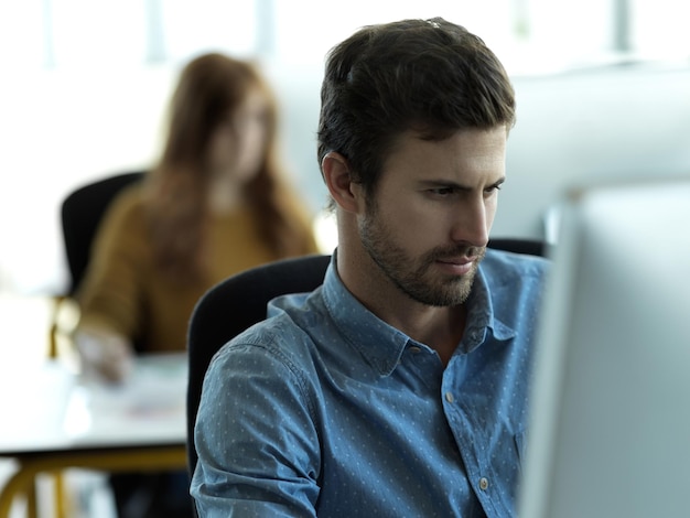 Seine Arbeit hat Vorrang Schnappschuss eines hübschen jungen Geschäftsmanns, der an seinem Schreibtisch im Büro arbeitet