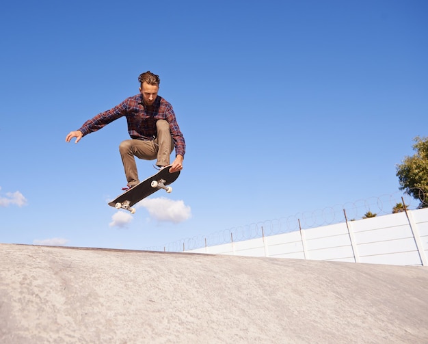 Seine Tricks perfektionieren Ein junger Mann, der Tricks auf seinem Skateboard im Skatepark macht