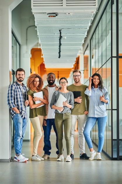 Seis jovens sorrindo e posando com laptops nas mãos