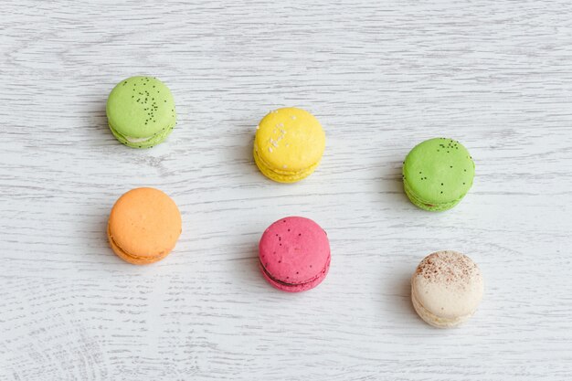 Seis macarons multicolores en una mesa de madera clara. Vista superior