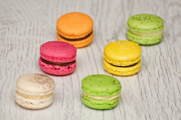 Seis macarons multicoloridos em uma mesa de madeira clara