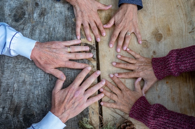 Seis mãos maduras caucasianas conectadas em fundo de madeira