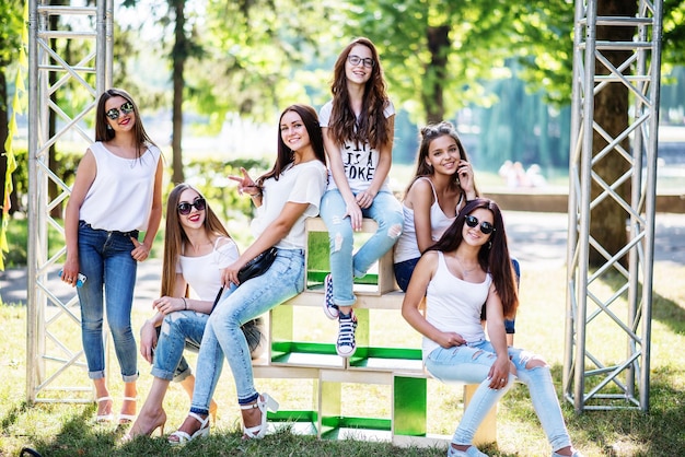 Seis meninas modelo maravilhosas posando em caixas de madeira no parque em um dia ensolarado