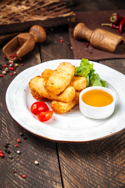 Seitenansicht auf frittiertem Mozzarella-Käse mit Soße auf dem Holztisch