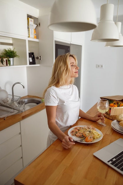 Seitenansicht auf kaukasische junge hübsche Frau, die Meeresfrüchtemittagessen mit Wein zu Mittag isst