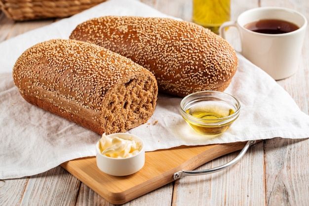 Seitenansicht auf Laibe von Weizen- und Roggenmehlbrot mit Butter auf dem hölzernen Hintergrund