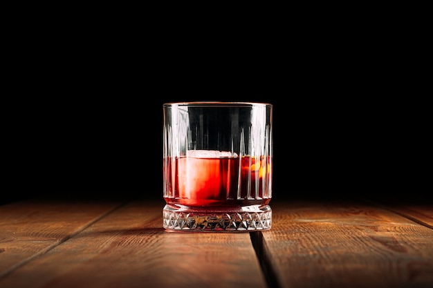 Seitenansicht auf Negroni-Cocktail im altmodischen Glas auf dem Holztisch
