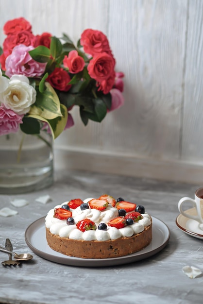 Seitenansicht auf süßem cremigem Kuchen mit Beeren und Tee