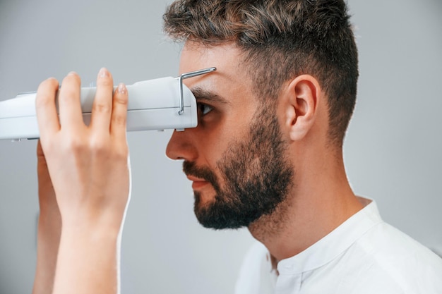 Seitenansicht Das Sehvermögen des Mannes wurde von einer Ärztin in der Klinik mit einem speziellen Augenoptikergerät überprüft