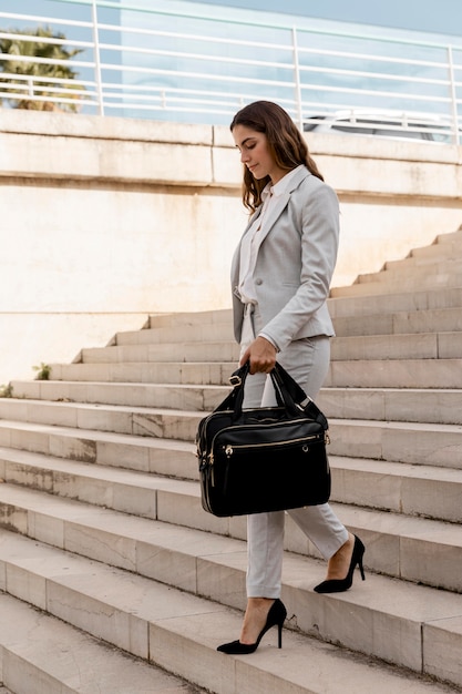 Foto seitenansicht der eleganten geschäftsfrau auf treppen im freien mit tasche