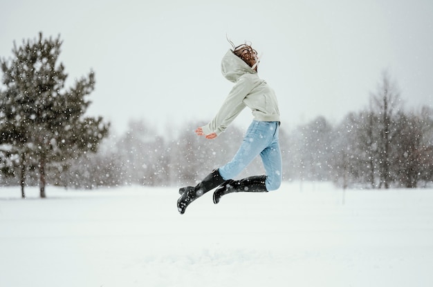 Seitenansicht der Frau, die in der Luft draußen im Winter springt