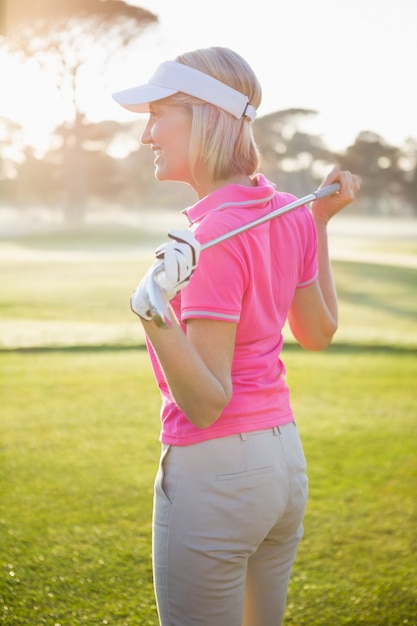 Seitenansicht der Golferin, die ihren Verein hält