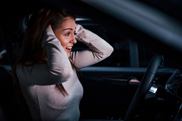 Seitenansicht der jungen Frau, die im brandneuen modernen Automobil gestikuliert.