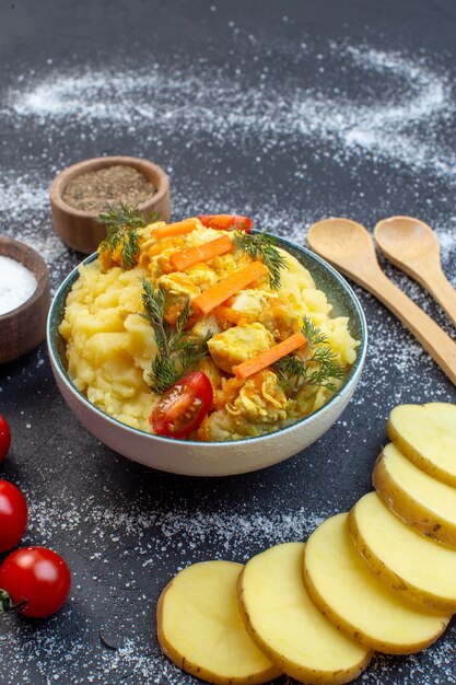 Seitenansicht der köstlichen Kartoffelmahlzeit mit frischem Gemüse Gewürzlöffel Tomaten auf weißem schwarzem Mischfarbhintergrund mit freiem Raum