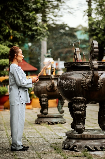 Foto seitenansicht der religiösen frau mit brennendem weihrauch am tempel