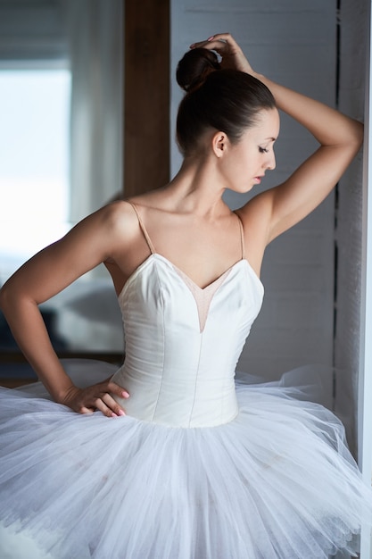 Seitenansicht der schönen Ballerina, die durch Fenster steht und schaut. Copyspace