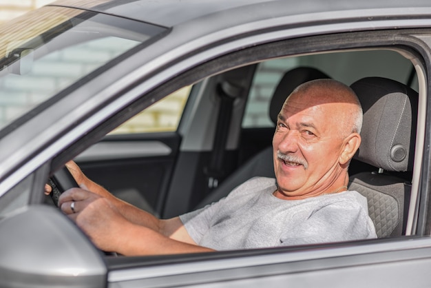 Seitenansicht des älteren Mannes, der ein Auto fährt