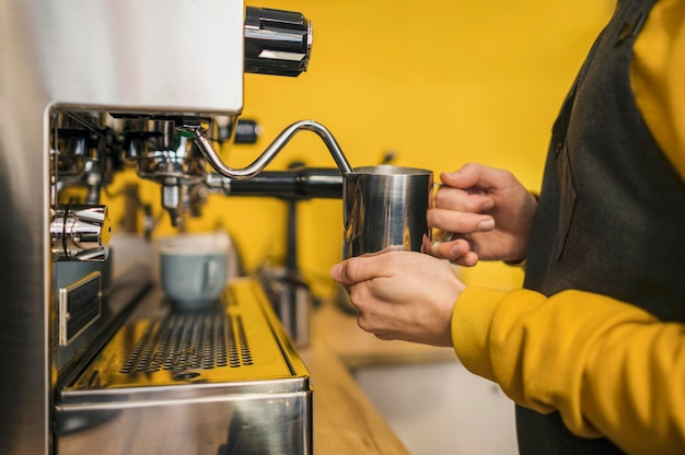 Foto seitenansicht des barista mit maschine zum aufschäumen von milch