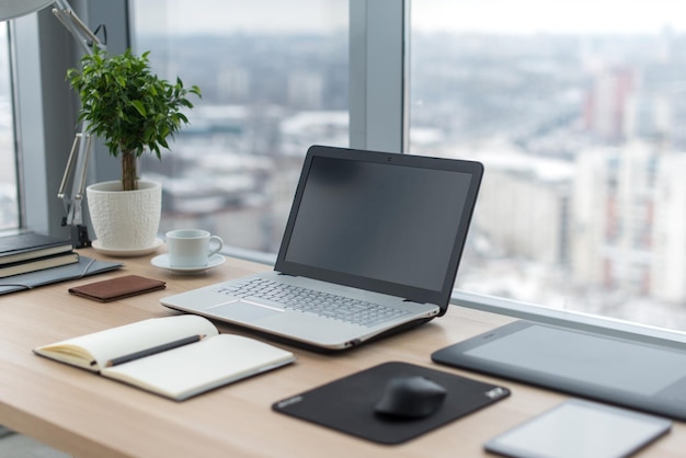 Seitenansicht des Bürodesktops mit leerem Laptop und verschiedenen Werkzeugen