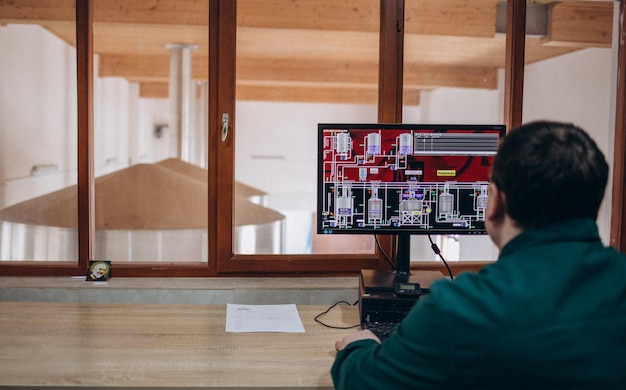 Seitenansicht des Herstellers, der ein digitales Tablet hält, während er in der Brauerei am Computer arbeitet