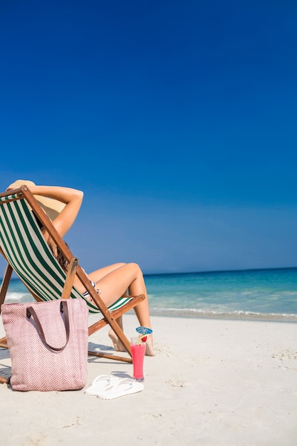 Seitenansicht des hübschen Brunette entspannend auf Klappstuhl am Strand