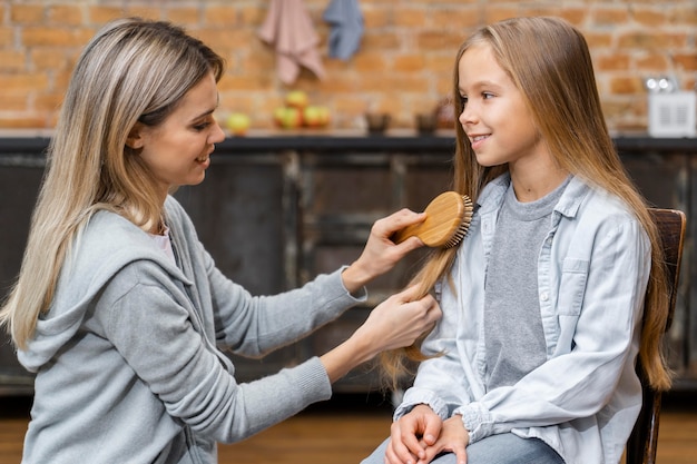 Foto seitenansicht des kleinen mädchens, das ihr haar durch friseur bürstet