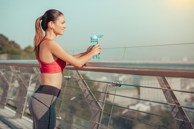 Seitenansicht des Läufers nach dem Training, der auf der Brücke steht und auf die Stadt blickt