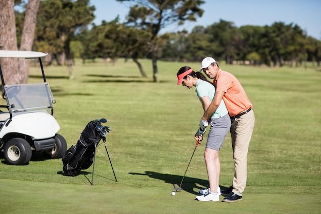 Seitenansicht des Mannes, der Frau lehrt, Golf zu spielen