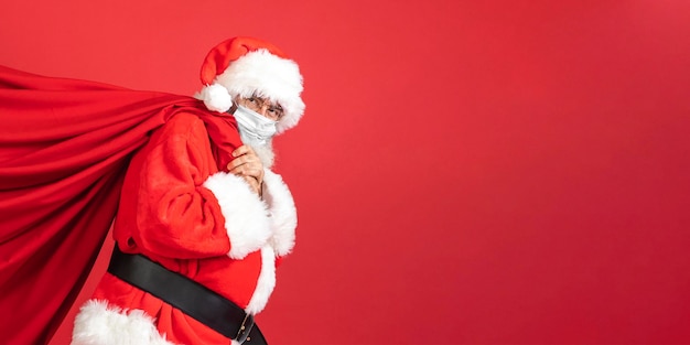 Seitenansicht des Mannes im Weihnachtsmannkostüm, das Geschenktüte trägt