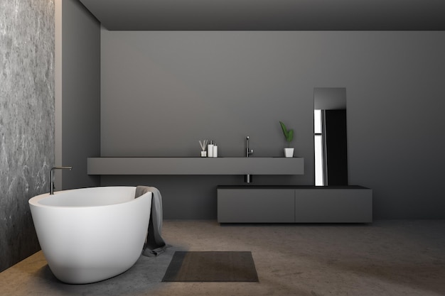 Seitenansicht des modernen Badezimmers mit grauen Betonwänden, Betonboden, weißer Badewanne mit Handtuch darauf und langem grauen Waschbecken mit Spiegel. 3D-Rendering