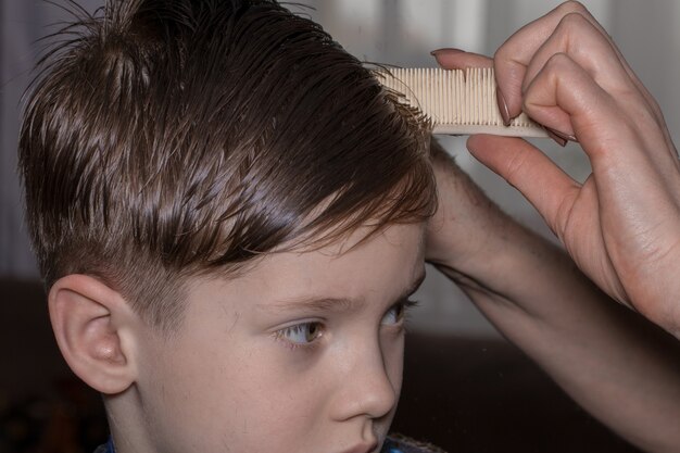 Seitenansicht des süßen kleinen Jungen, der sich vom Friseur im Friseursalon die Haare schneiden lässt.