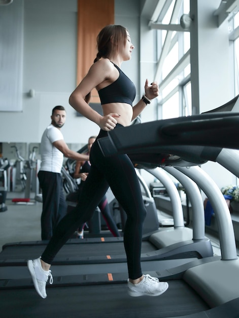 Seitenansicht Eine junge Frau arbeitet auf einem Laufband in einem gesunden Lebensstil eines Fitnesscenters