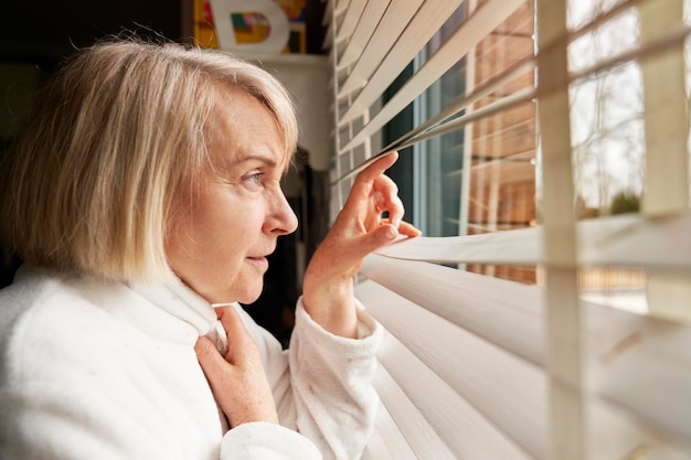 Seitenansicht einer älteren Frau, die aus dem Fenster schaut