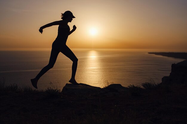 Seitenansicht einer Fitnessfrau, die auf einer Straße am Meer läuft