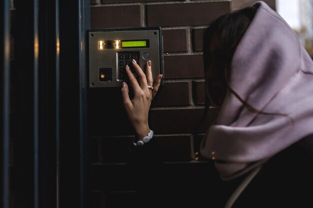 Seitenansicht einer Frau, die das Sicherheitssystem am Eingang des Hauses benutzt