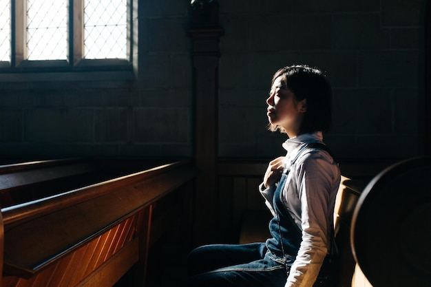 Foto seitenansicht einer frau, die in der kirche sitzt und wegblickt